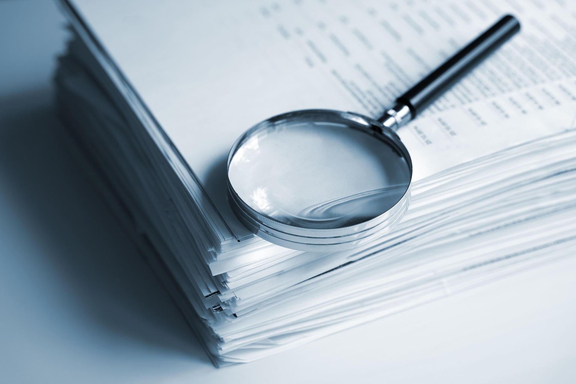 Magnifying glass on a stack of documents